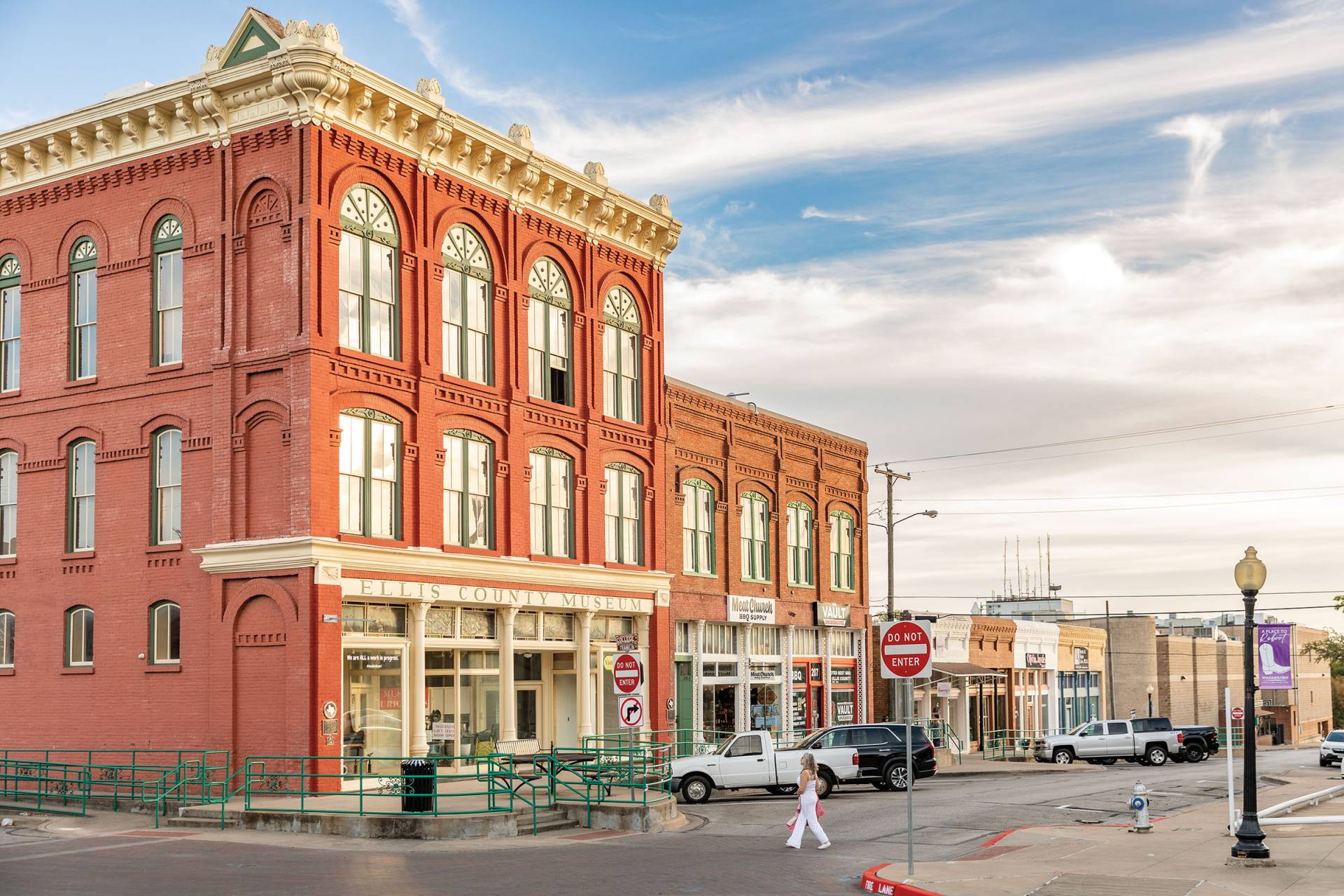 Historic Ellis County Museum building in downtown Waxahachie, TX, featuring red brick architecture along a quiet small-town street.