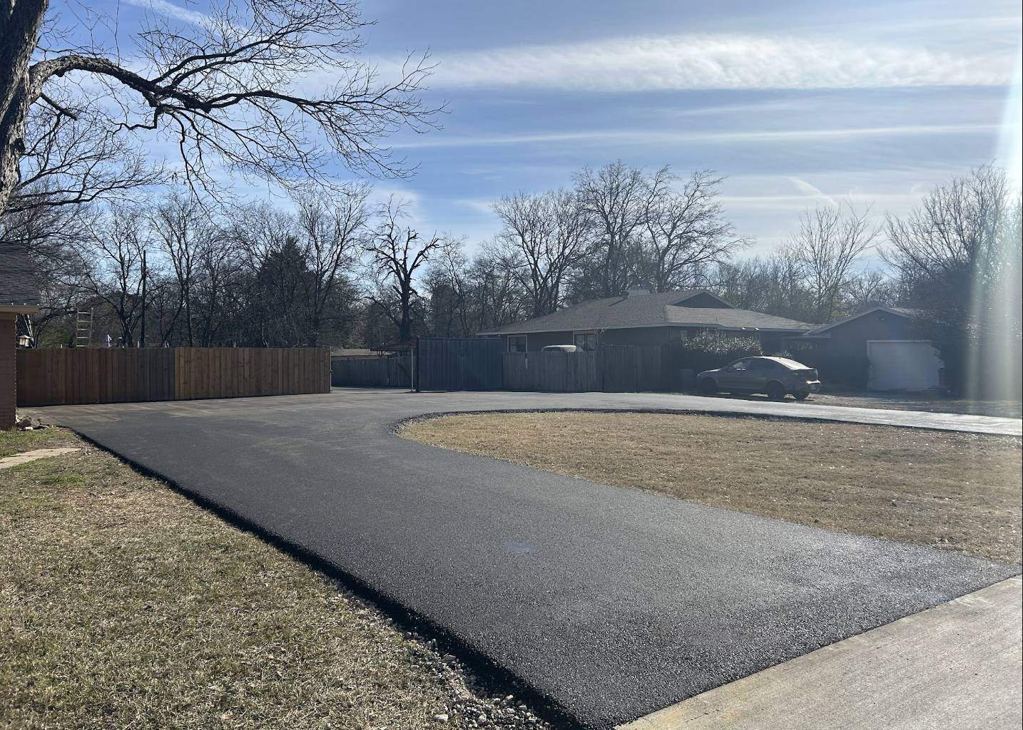 Freshly paved circular asphalt driveway for a suburban home in Dallas Texas completed by PMG Paving
