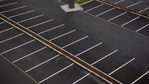 High-angle view of an empty commercial parking lot featuring freshly sealcoated asphalt and clean white line striping